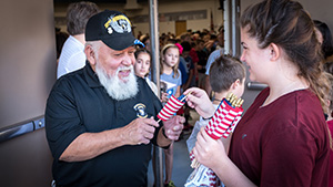 Elementary student hands a small American flag to older veteran